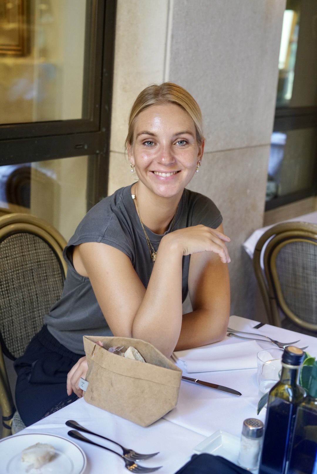 Laura smiling at a café table with fresh bread